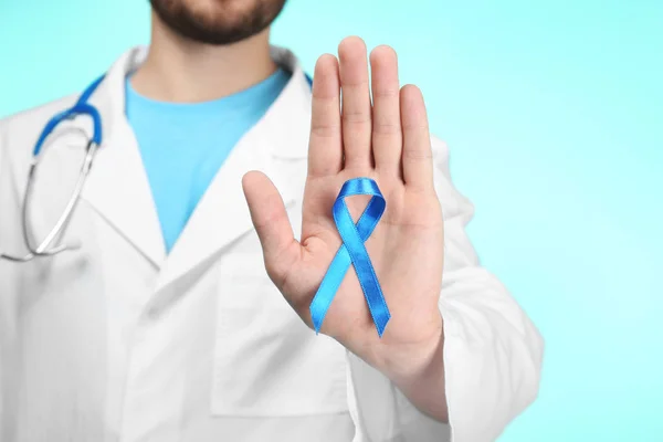 Doutor mostrando fita azul no fundo da cor. Conceito de consciência do câncer — Fotografia de Stock