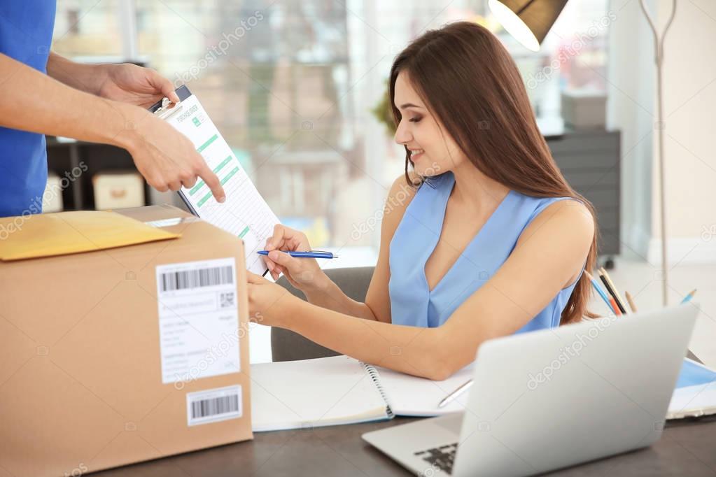 Woman signing documents after receiving parcel from courier