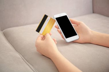 Cep telefonu ve kredi kartı evde olan kadın. Internet alışveriş kavramı