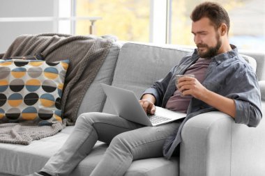 Dizüstü bilgisayar ve kahve evde koltukta oturan rahat adam