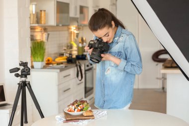 Genç kadın mutfakta natürmort fotoğraf çekmeye profesyonel kamera ile