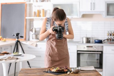 Genç kadın mutfakta natürmort fotoğraf çekmeye profesyonel kamera ile