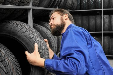Otomobil deposunda otomobil lastiği tutan erkek makinist