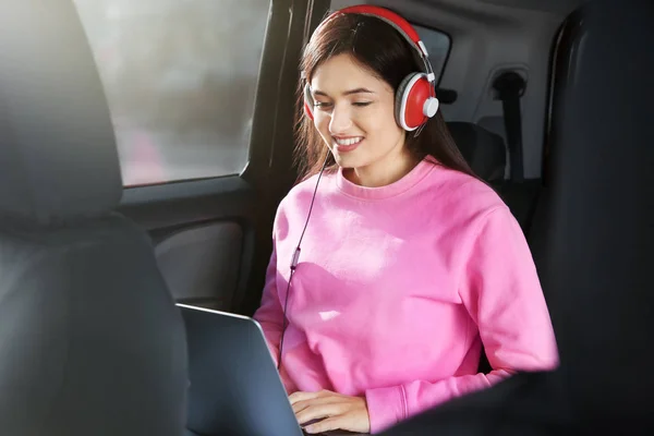 Mujer escuchando audiolibro a través de auriculares en el coche — Foto de Stock