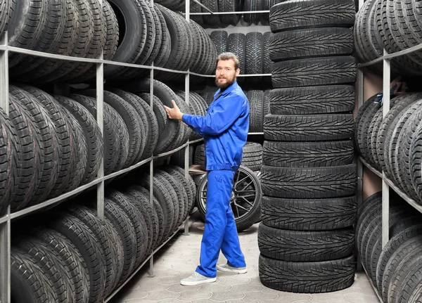 Masculino mecânico segurando pneu de carro na loja de automóveis — Fotografia de Stock