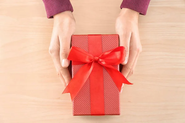 Frau hält Paket Geschenkschachtel auf Holz Hintergrund — Stockfoto