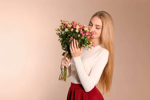 Vacker ung kvinna med bukett rosor på färg bakgrund — Stockfoto