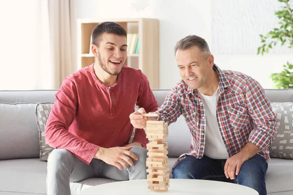 Зрілий чоловік грає в настільну гру зі своїм сином вдома — стокове фото