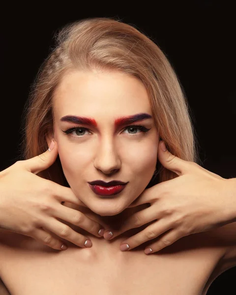 Junge Frau mit gefärbten Augenbrauen auf schwarzem Hintergrund — Stockfoto