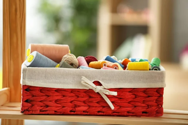 Wicker box with color sewing threads and crocheting clews on shelf indoors — Stock Photo, Image