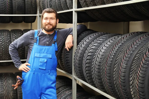 Meccanico maschio con pneumatici per auto nel negozio di automobili — Foto Stock