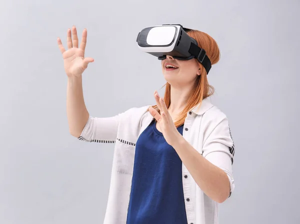 Mujer con auriculares de realidad virtual sobre fondo gris —  Fotos de Stock