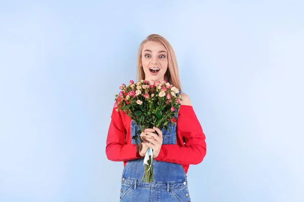 色の背景にバラの花束を持つ美しい若い女性 — ストック写真