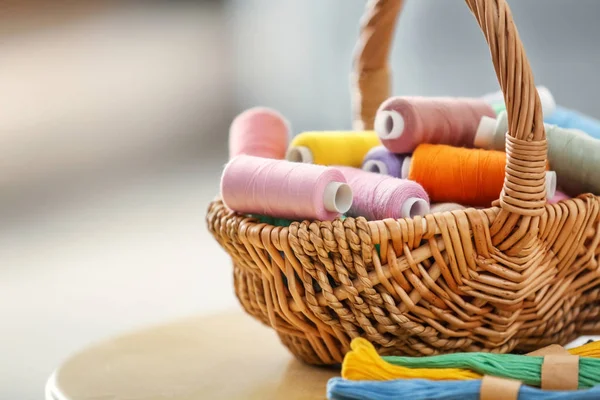 Wicker basket with sewing and mouline threads on table