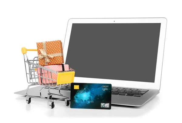 Portátil, tarjeta de crédito y pequeño carrito de compras con cajas de regalo sobre fondo blanco. Concepto de compras por Internet —  Fotos de Stock