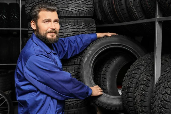 Mechanik mężczyzna trzyma samochodów opon w sklepie motoryzacyjnym — Zdjęcie stockowe