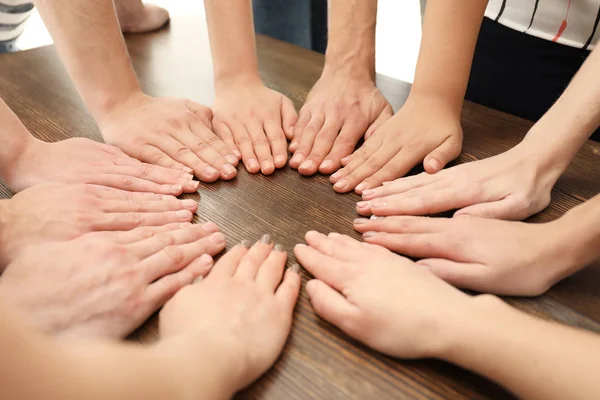 Grupa ludzi, łącząc ręce na drewnianym stole jako symbol jedności — Zdjęcie stockowe