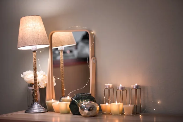 Горящие свечи и современное зеркало на столе — стоковое фото