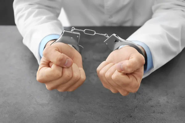 Doctor in handcuffs at workplace, closeup — Stock Photo, Image