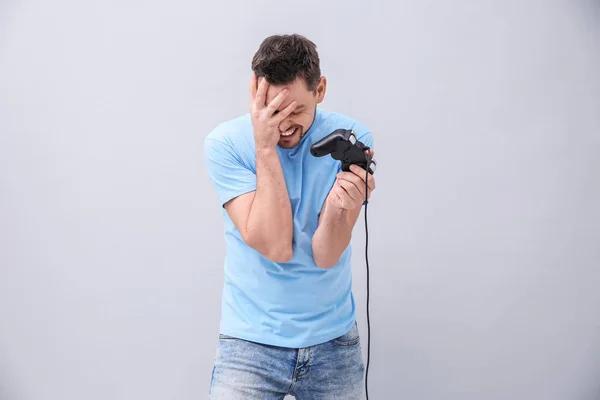 Homem perturbado com controlador de vídeo game em fundo cinza — Fotografia de Stock