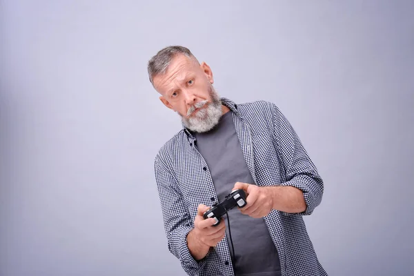 Emotionele senior man afspelen van video game op grijze achtergrond — Stockfoto