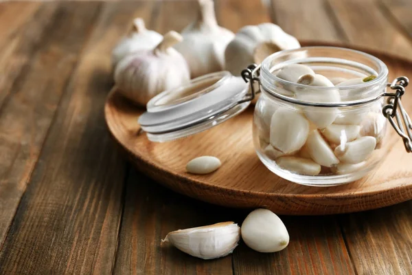 Jar with garlic cloves on plate — Stock Photo, Image