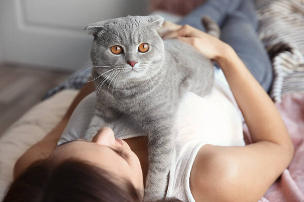 Young woman with cute pet cat on bed at home