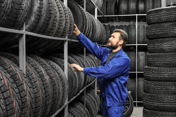 Meccanico maschio con pneumatici per auto nel negozio di automobili — Foto Stock