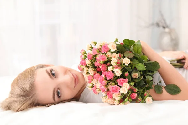 Mulher bonita com buquê de rosas na cama em casa — Fotografia de Stock