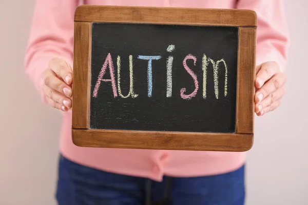 Женщина держит доску со словом "аутизм" на светлом фоне — стоковое фото