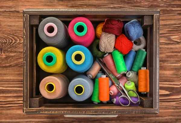 Wooden box with color sewing threads and crocheting clews on table, top view — Stock Photo, Image