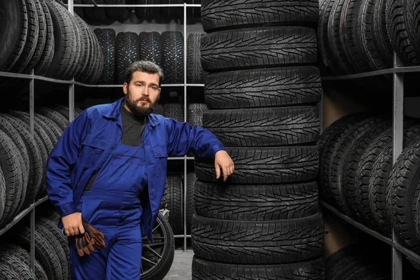 Mecánico masculino cerca de neumáticos en la tienda de automóviles —  Fotos de Stock