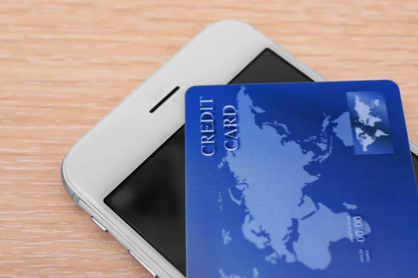 Carta di credito e cellulare sul tavolo, primo piano. Internet shopping concept — Foto Stock