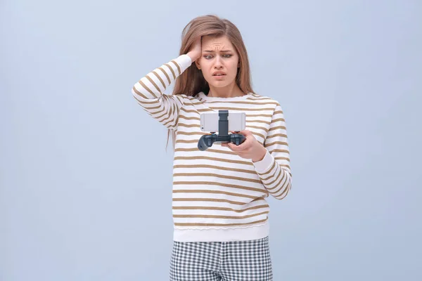 Upprörd kvinna med videospel controller för smartphone på färgbakgrund — Stockfoto