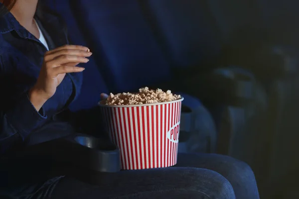 Young woman with bucket of tasty popcorn in cinema — Stock Photo, Image