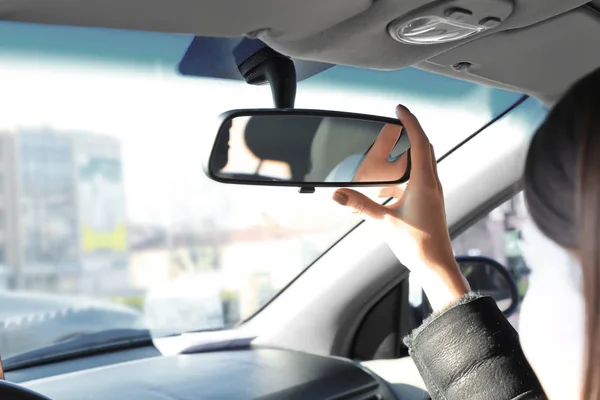 Mulher ajustando espelho retrovisor no carro — Fotografia de Stock