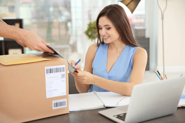 Frau unterschreibt Dokumente, nachdem sie Paket von Kurier erhalten hat — Stockfoto