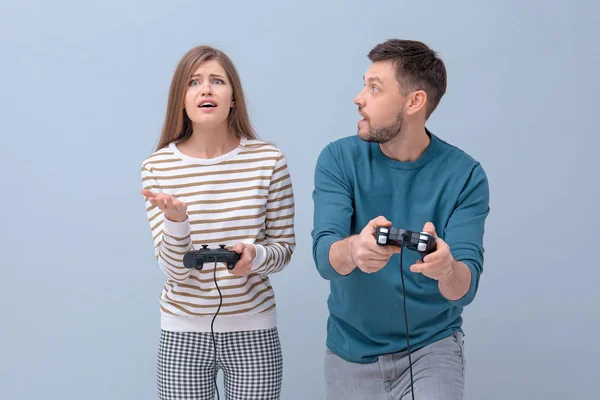 Emotionales Paar mit Videospielcontrollern auf farbigem Hintergrund — Stockfoto