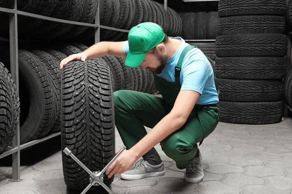 Male mechanic with spanner and car tire in automobile store — Stock Photo, Image