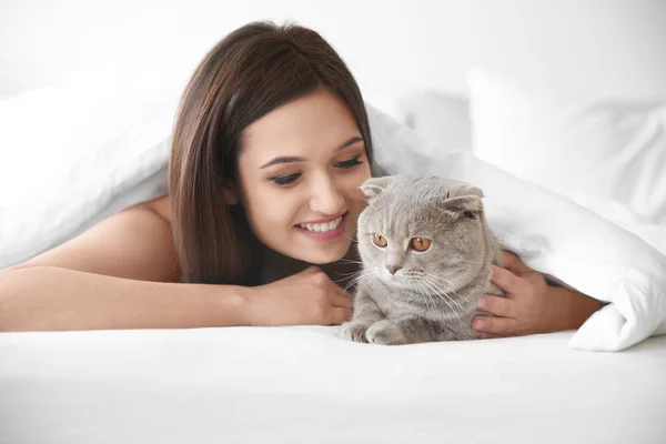 Jovem com gato de estimação bonito na cama em casa — Fotografia de Stock