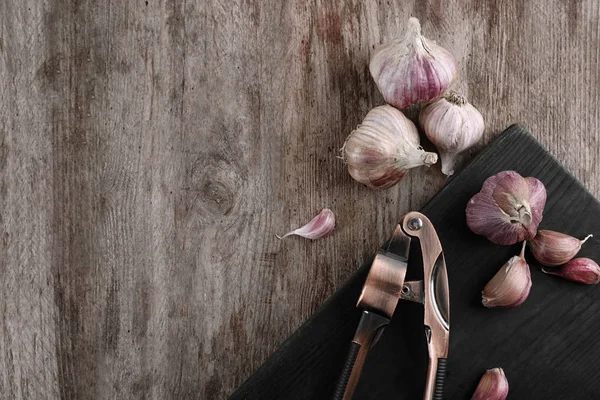 Ajo fresco y trituradora sobre tabla de madera —  Fotos de Stock