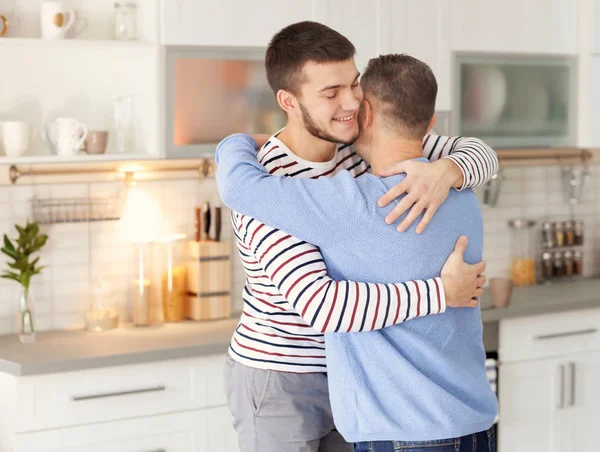 Mature man hugging his son at home — Stock Photo, Image