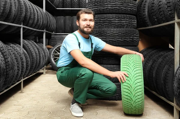Mecánico masculino con neumático de coche de color en la tienda de automóviles —  Fotos de Stock