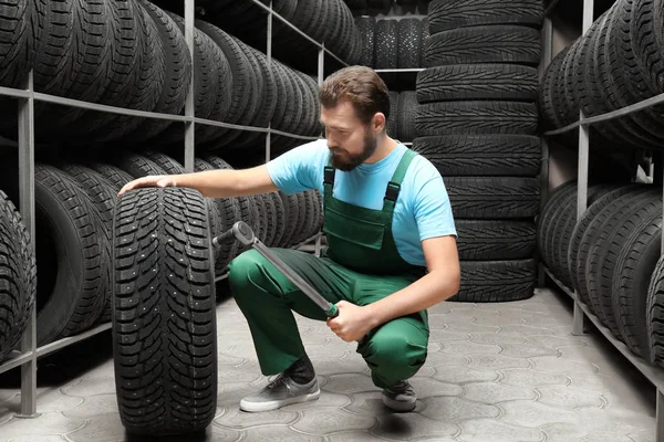 Meccanico maschio con chiave inglese e pneumatico per auto nel negozio di automobili — Foto Stock