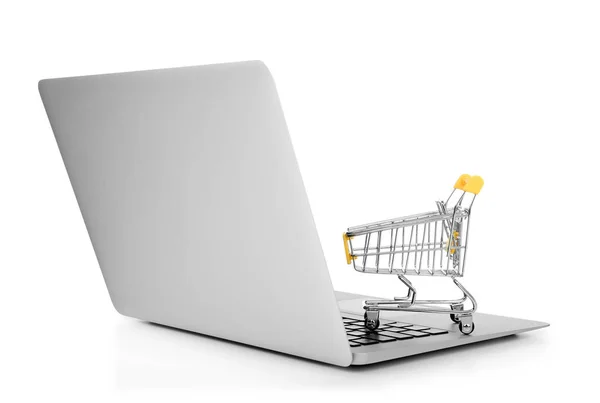 Laptop e piccolo carrello su sfondo bianco. Internet shopping concept — Foto Stock