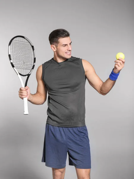 Porträt eines gutaussehenden Mannes beim Tennisspielen vor grauem Hintergrund — Stockfoto