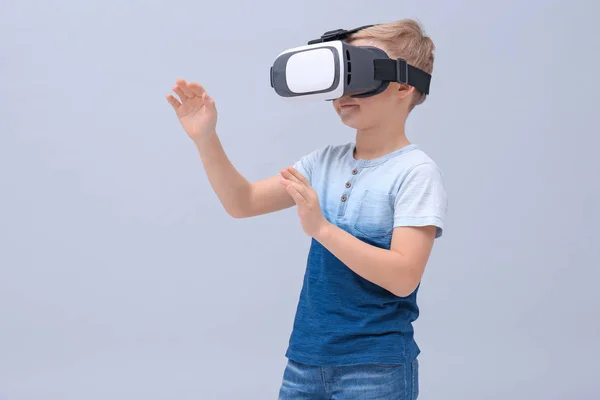 Lindo chico con auriculares de realidad virtual en el fondo de color — Foto de Stock