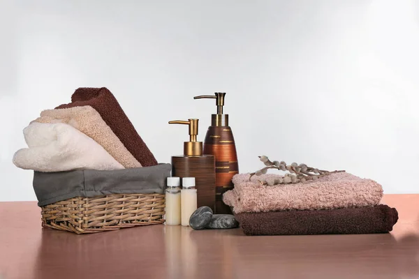 Cesta de mimbre con juego de toallas limpias y artículos de tocador sobre mesa de madera sobre fondo blanco — Foto de Stock