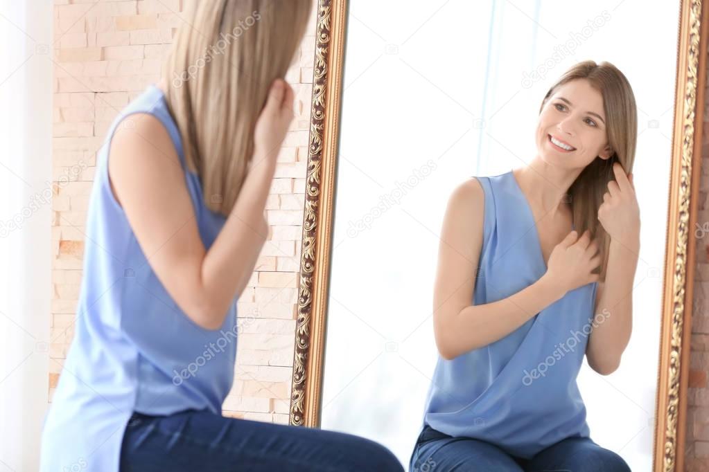 Young woman looking at herself in mirror indoors