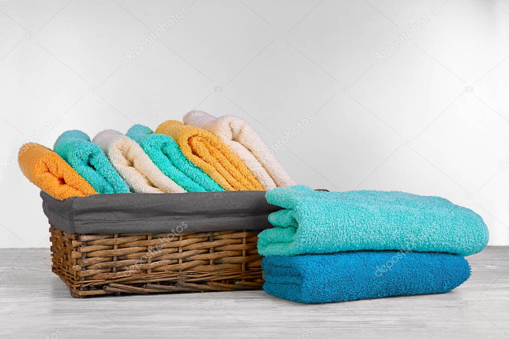 Wicker basket with fresh towels on table against white background